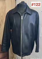 Front view of men's black leather jacket on a mannequin showing zipper closure and collar.