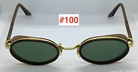 Front view of oval gold-tone metal frame sunglasses with green lenses