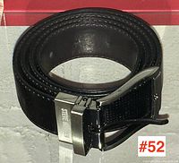 Rolled black leather belt with perforated pattern and silver-tone buckle engraved with STEVE MADDEN.