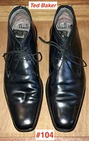 Top view of pair of black leather Ted Baker men's dress shoes showing square toes, laces, creasing on leather.