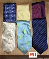 Lot of six vintage silk ties arrayed on wooden surface, showing varied colors and patterns.