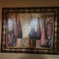 Framed art piece showing abstract vases with branch and leaf motifs in warm earth tones, housed in an antique finish gold and brown frame.