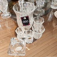 Four mini crystal vases, crystal candle holder, and one medium crystal vase displayed together on a wooden surface