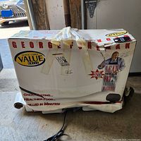 Boxed large George Foreman grill with taped packaging showing front branding and health claims.