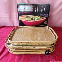 Stack of four rectangular bamboo wicker serving trays showing bamboo weaving and framed edges