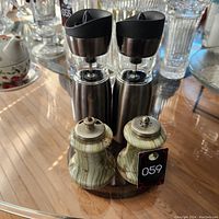 Photo showing two pairs of salt and pepper sets: one modern battery-operated stainless steel grinders and one with a marble look design