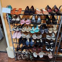 Full rack of women's shoes showing multiple pairs of used footwear arranged on a metal rack.