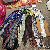 Overview of ten women's scarfs laid on floor, displaying different patterns and colors.
