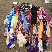 Full assortment of about 18 womens scarves showing various colors and patterns on hangers
