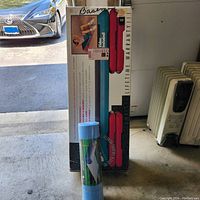 Boxed adjustable workout step board and rolled blue exercise mat next to it.