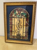 Framed handcrafted artwork showing floral stained glass style design with detailed gold frame.