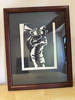 Framed black and white print of a trumpet player shown in profile.