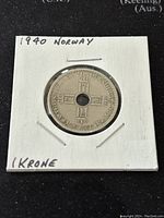 Front side of the 1940 Norway 1 Krone coin in protective cardboard holder, showing the date, cross design, and text.