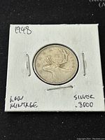 Front side of 1948 Canadian 25 cent coin with caribou design, noting low mintage and .8000 silver content