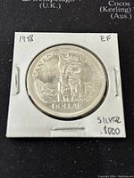 Reverse side of the 1958 Canadian silver dollar coin featuring totem pole design, date markings, and silver content noted on holder.