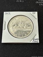 Obverse side of the 1959 Canadian silver one dollar coin showing the canoeing scene and inscriptions.