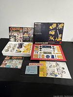 Original boxes and documentation for Capsela 400 and Meccano 3 sets along with parts arranged for display.