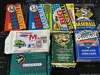 Photo of 7 assorted sealed baseball card packs and baseball playing cards.