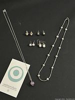 Full lot showing two necklaces and four pairs of earrings on black background, with a Sterling Simplicity tag in view