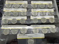 Photo of various US Jefferson nickels from 1960 to 1982 in plastic coin holders with handwritten year labels.