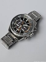 Front angle view showing black dial, chronograph subdials, and stainless steel bracelet.