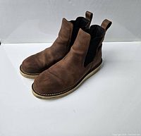 Side angled view of the brown leather boots showing the elastic panel and pull tab features.