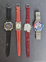 Lot of four vintage wristwatches displayed flat showing front faces and straps.
