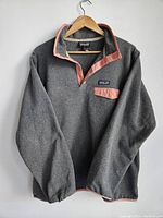 Front view of grey Patagonia Synchilla Snap-T fleece pullover with pink trim and chest pocket.