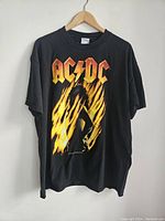 Full view of the vintage black AC/DC T-shirt showing front graphic and logo on hanger.