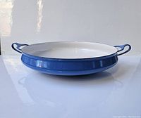 Side angle view of the vintage Dansk paella pan showing the blue exterior and side handles.