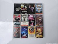All twelve cassette tapes laid out in three rows of four, showing album covers and titles of vintage heavy metal music albums.