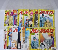 Collection of 17 MAD magazines arranged showing front covers, mostly yellow background with red MAD logo, various humorous cover art from late 1990s.