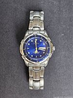 Front view of vintage Swiss diving watch with blue dial and stainless steel bracelet on black background.