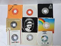 Top view of all 10 vintage 7-inch vinyl singles spread out showing various record labels and outer sleeves including the Sex Pistols cover