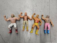 Four WWF wrestling action figures placed side by side on a grey textured surface, showing full-body front view.