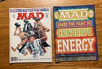 Front covers of two MAD Magazines, one a Star Wars musical parody cover and the other promoting energy conservation.