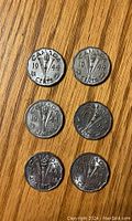 Reverse sides of six 1944 Canadian 5 cent nickels showing three maple leaves design and denomination.