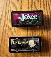 Plastic display boxes with artwork of Joker and Lex Luthor on lids.