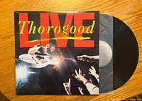 Front cover of Thorogood Live vinyl album showing artist performing live on stage with bright lighting and album title.