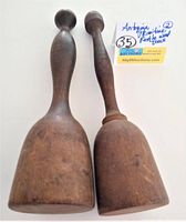 Front view of two antique wooden pestles showing their shapes and sizes, with an auction tag visible