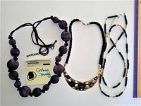 Three costume jewelry necklaces laid flat on white surface showing details and necklace lengths next to a ruler.