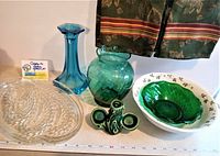 Photo showing entire lot including blue candlestick holder, green vase, clear snack plates, ceramic salt and pepper holder, green swirl glass bowl inside larger floral printed bowl, and kitchen towels.