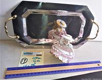 Photo showing the Bloomer Girl figurine posed in front of the reflective 24K flower etched serving tray with handles. A ruler is placed below for size reference.