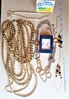 Lot of 5 jewelry items including 4 necklaces and 1 boxed pair of sterling silver rhinestone earrings displayed on table with measuring stick.