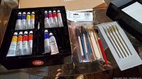 Overview of acrylic paint tubes and two brushes sets in packaging