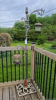 Full view of the metal shepherd's hook bird feeder stand with two feeders hanging and visible grass background.