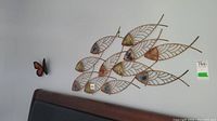 Overall view showing multiple metal fish in wire-frame leaf shapes with colorful triangular heads and a small metal butterfly on the side.
