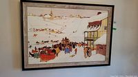 Framed print hanging on wall showing a winter scene with horses, sleighs, and people in snow-covered village.