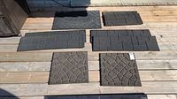 Top-down photo showing all six rubber mats and treads arranged on wood deck. Includes one large 'WELCOME' mat and five varying shapes and sizes of black treads with different patterns.