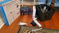 Full view of Nintendo Wii console, controllers, power cables, Sports Pack 8-in-1 box, and Virtual Reality 3D Headset box on floor